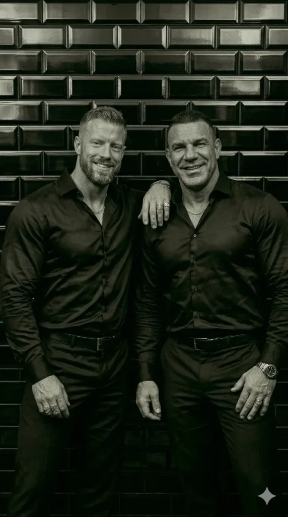 "Dos hombres vestidos elegantemente con camisas de seda negra y pantalón negro en tendencia. Cuerpos esculturales de gimnasio. - Parcegay: Guía de consumo, tendencias y experiencias para el hombre gay."